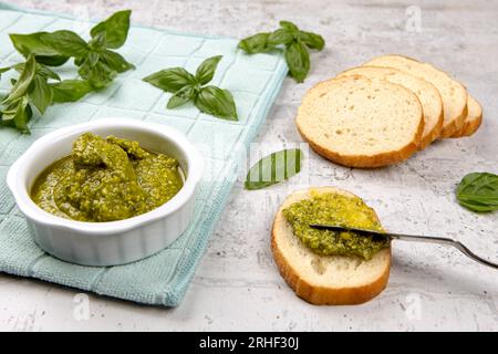 Ein Foto, wie frisches Pesto auf kleine Brotscheiben im Studio verteilt wird. Stockfoto