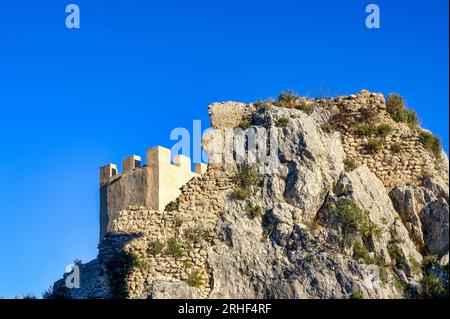 Guadalest, Alicante, Spanien, Turm mit Merlonen in der Festung auf einem Hügel. Die mittelalterliche Burg ist durch die umliegenden Berge geschützt. Stockfoto