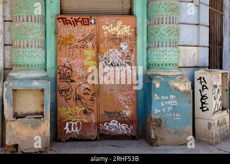 Havanna, Kuba, geschlossen und dreckige Metalltür mit Graffiti bedeckt. Das Gebäude befindet sich in einem Gebäude im Kolonialstil mit einer Veranda. Stockfoto