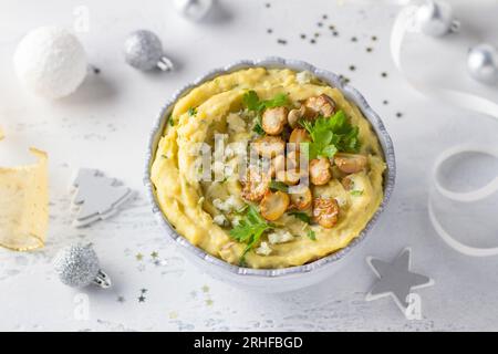 Kartoffelpüree mit Pilzen und Blauschimmelkäse auf graublauem Hintergrund mit weißen und silbernen Dekorationen. Hausgemachtes Essen, Festtagsessen. Stockfoto