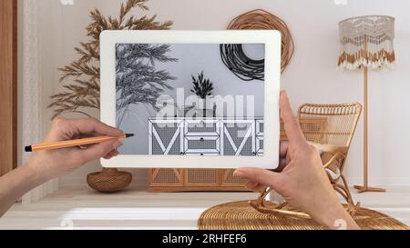 Hände halten und zeichnen auf dem Tablet mit Bohemian Wohnzimmer in Boho-Stil Details CAD-Skizze. Echte fertige Innenausstattung im Hintergrund, Architekt Stockfoto