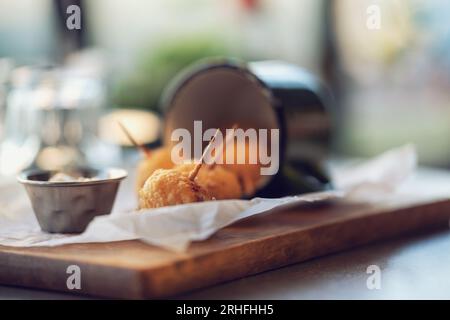 Frittierte Käsebällchen. Käsebällchen in einem altmodischen Becher. Käsebällchen werden in einem Restaurant auf dem Tisch serviert. Stockfoto