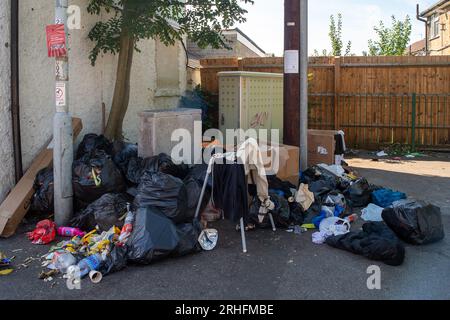 Chalvey, Slough, Berkshire, Großbritannien. 16. August 2023. Obwohl Chalvey einen kostenlosen Abfalltipp für die Bewohner hat, werden verrottete Lebensmittel, Kleidung und Haushaltsmüll weiterhin regelmäßig von Bewohnern in Chalvey, Slough, Berkshire, auf den Straßen entsorgt. Ein deutliches Schild des Slough Borough Council informiert die Bewohner, dass die Gegend überwacht wird und dass Flugtipps zu einer Geldstrafe von 50.000 £ führen könnten. Dies hat sich noch verschlimmert, seit der Rat von Slough Borough kürzlich eine Änderung der Abfalleimer-Sammlungen der Bewohner eingeführt hat, um die Bewohner zu ermutigen, mehr zu recyceln. Graue Behälter mit allgemeinem Abfall einschließlich Stockfoto