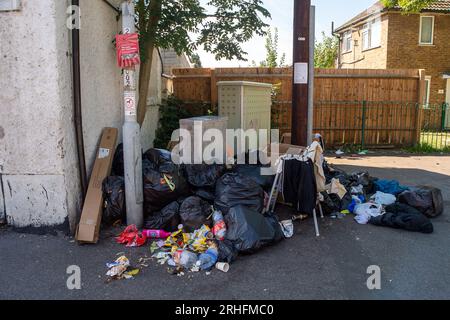 Chalvey, Slough, Berkshire, Großbritannien. 16. August 2023. Obwohl Chalvey einen kostenlosen Abfalltipp für die Bewohner hat, werden verrottete Lebensmittel, Kleidung und Haushaltsmüll weiterhin regelmäßig von Bewohnern in Chalvey, Slough, Berkshire, auf den Straßen entsorgt. Ein deutliches Schild des Slough Borough Council informiert die Bewohner, dass die Gegend überwacht wird und dass Flugtipps zu einer Geldstrafe von 50.000 £ führen könnten. Dies hat sich noch verschlimmert, seit der Rat von Slough Borough kürzlich eine Änderung der Abfalleimer-Sammlungen der Bewohner eingeführt hat, um die Bewohner zu ermutigen, mehr zu recyceln. Graue Behälter mit allgemeinem Abfall einschließlich Stockfoto