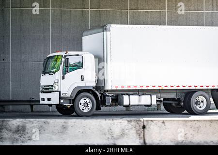 Industriestandard, sauberes weißes Day Cab, mittleres Fahrerhaus über Sattelzugmaschine für den Transport von gewerblicher Fracht in Kastenwagen auf der geteilten Höhe Stockfoto