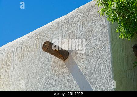 Details des Gebäudes im adobe-Stil mit freiliegendem hölzernen Viga-Balken am blauen Himmel Stockfoto