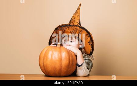 Halloween-Kinder. Junge im Hexenhut mit Halloween-Kürbis. 31. Oktober. Vorbereitung auf Halloween-Feiertage. Trick oder Belohnung. Wenig Stockfoto