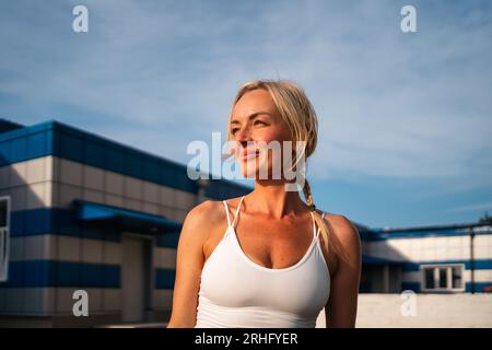 Porträt einer mittelalterlichen, wunderschönen blonden Frau im Sonnenuntergang draußen. Weibliche Sportlerin mit Kopfschuss im Freien. Stockfoto