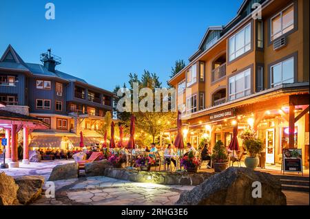 An einem Sommerabend speisen Touristen im Freien auf den Restaurantterrassen im Whistler Village. Whistler BC, Kanada. Stockfoto