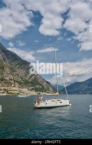 Segelboot mit Besatzung vor der Küste von Limone Sul Garda am Westufer des Gardasees, Lago di Garda in Italien Stockfoto