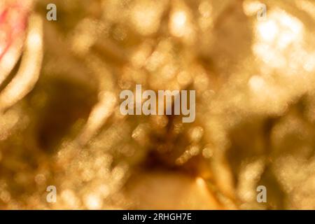 Glänzend gelbe, defokussierte Blattgoldfolie, glitzernder Hintergrund Stockfoto