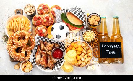 Tischszene mit einer großen Auswahl an Imbiss- und Fast Food-Gerichten. Hamburger, Pizza, gebratenes Huhn und Snacks auf weißem Hintergrund. Draufsicht. Stockfoto