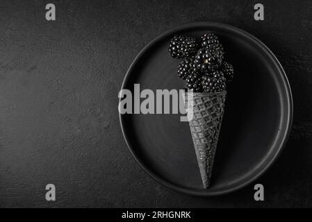 Brombeeren auf schwarzem Hintergrund in einem Eiskegel Stockfoto