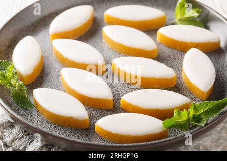 Provenzalische französische Calisson-Süßigkeiten aus Melone, Mandel und Orange, bedeckt mit weißer Königszuckerglasur, auf einem Teller auf dem Tisch. Horizontal Stockfoto