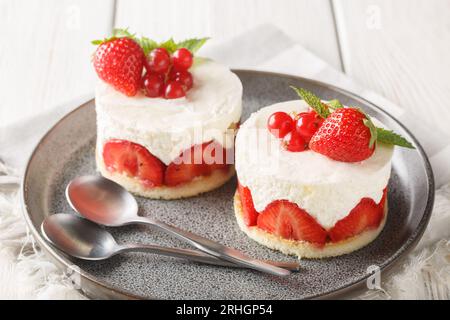 Französische Erdbeeren-Fraisier-Minikuchen auf dem Teller auf dem Tisch. Horizontal Stockfoto