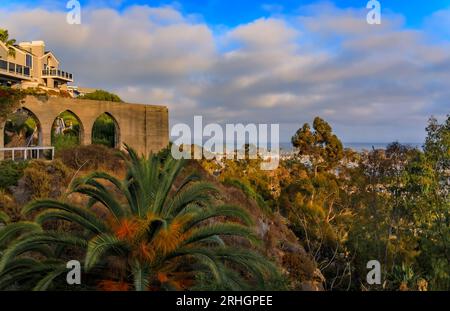 Sonnenuntergang über Luxushäusern, einer wunderschönen Palme und Booten im Hafen von Dana Point, Orange County in Südkalifornien an einem bewölkten Tag, Panoramablick Stockfoto