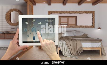 Smart Remote Home Control System auf einem digitalen Tablet. Gerät mit App-Symbolen. Japandi-Schlafzimmer mit Doppelbett und Waschbecken, Architektur-Innenausstattung Stockfoto