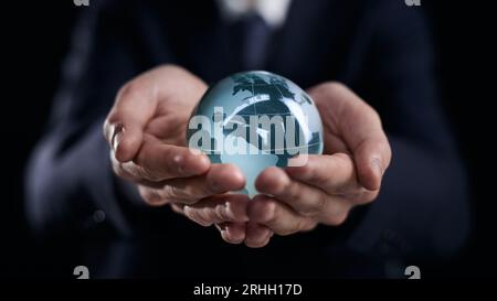 Geschäftsmann hält Glaskugel mit Kontinenten in Händen Stockfoto