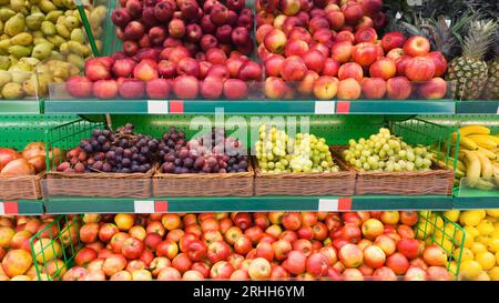 Supermarktregale mit Obst. Äpfel, Trauben und andere süße Früchte, die im Schaufenster verkauft werden Stockfoto