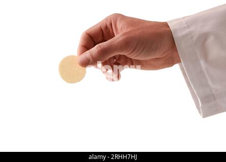 Detail der Hand eines Priesters in Kommunion mit einem Wirt, geweiht als der Körper Christi, mit einem weißen isolierten Hintergrund Stockfoto