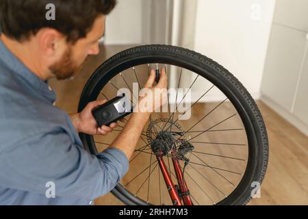 Nahaufnahme eines Mannes, der den Luftdruck in den Rädern des Motorrads prüft und zu Hause Luft in die Reifen einfüllt Stockfoto