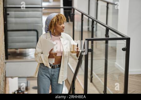 Positive afroamerikanische Frau mit Klammern, die Papiere halten, Startup-Projekt, Coworking, Treppen Stockfoto