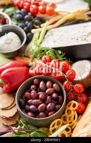 Oliven im Vordergrund. Tisch voller mediterraner Vorspeisen, Tapas oder Antipasto. Auswahl an italienischen Speisen. Köstlicher Snack auf einer Party oder Picknick Stockfoto