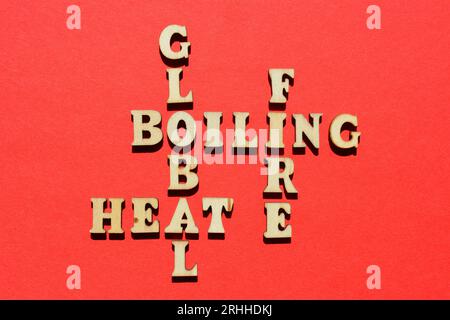 Global, kochend, Feuer, Hitze, Wörter in Holzbuchstaben in Kreuzworträtsel-Form isoliert auf rotem Hintergrund Stockfoto