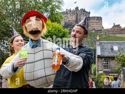 Edinburgh, Schottland, Großbritannien, 17. August 2023. Bill’s 44th at Edinburgh Festival Fringe: Bill umarmt alle schottischen Dinge, trägt einen See You Jimmy Tam O’Shanter Hut und trinkt Irn Bru mit Edinburgh Castle im Hintergrund, gesehen vom berühmten Vennel. Diese Marionettenshow stammt von den New Yorker Puppenspielern Dorothy James und Andy Manjuck. Sally Anderson/Alamy Live News Stockfoto