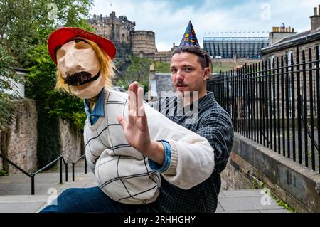 Edinburgh, Schottland, Großbritannien, 17. August 2023. Bill’s 44th at Edinburgh Festival Fringe: Bill umarmt alle schottischen Dinge, trägt einen See You Jimmy Tam O’Shanter Hut und trinkt Irn Bru mit Edinburgh Castle im Hintergrund, gesehen vom berühmten Vennel. Diese Marionettenshow stammt von den New Yorker Puppenspielern Dorothy James und Andy Manjuck (Andy hier gesehen). Sally Anderson/Alamy Live News Stockfoto