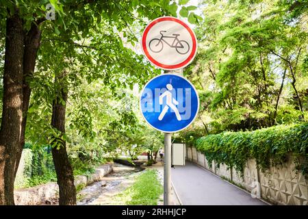 Ansicht eines generischen Schilds „kein Radfahren“ auf einem Fußgängerweg. Das Schild „kein Radfahren“ weist darauf hin, dass Fahrräder, E-Fahrräder, Roller, E-Scooter und verwendet werden Stockfoto