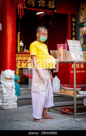 Ein alter Thailänder steht vor einem chinesischen Tempel in China Town, Bangkok, Thailand. Stockfoto