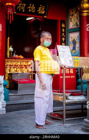 Ein alter Thailänder steht vor einem chinesischen Tempel in China Town, Bangkok, Thailand. Stockfoto