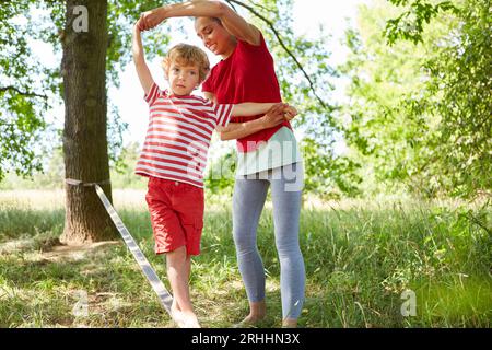 Ein süßer Sohn, der sich im Garten herumschlängelt, während die Mutter im Garten hilft Stockfoto