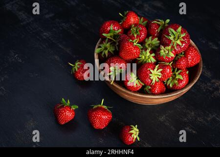 Rote reife Erdbeere auf dunklem Hintergrund. Frische Erdbeeren in der Schüssel Stockfoto
