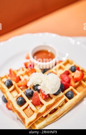 Klassische Wiener Waffeln mit Eis, Beeren und Ahornsirup. Frühstück im Café. Tisch im Restaurant. Stockfoto
