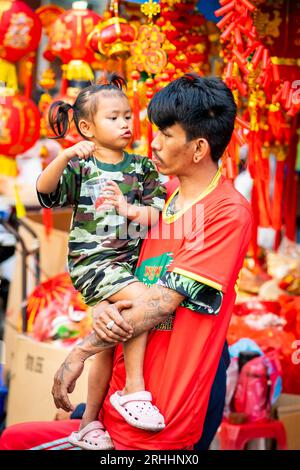 Ein stolzer junger Thai-Vater spielt mit seiner schönen kleinen Tochter in China Town, Bangkok, Thailand. Stockfoto