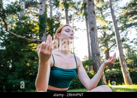 Ein Mädchen meditiert während einer Yogastunde unter freiem Himmel in einem öffentlichen Park Stockfoto