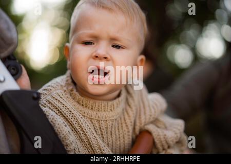 Niedlicher kaukasischer kleiner Junge, der in einem Buggy sitzt, ängstlich oder verärgert Stockfoto