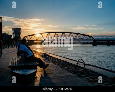 Nijmegen, Niederlande. August 2023. Ein Mann sitzt in der Nähe des Wall River während des Sonnenuntergangs. Nach einigen wechselhaften Wochen können sich die Niederlande auf das Sommerwetter in dieser Woche freuen. Die Temperaturen sind gestiegen und es gibt viel Platz für Sonnenschein. In den folgenden Tagen bleibt es meist trocken und die Sonne scheint ausgiebig, so dass Temperaturen zwischen 22 und 28 Grad zu erwarten sind. (Foto: Ana Fernandez/SOPA Images/SIPA USA) Credit: SIPA USA/Alamy Live News Stockfoto