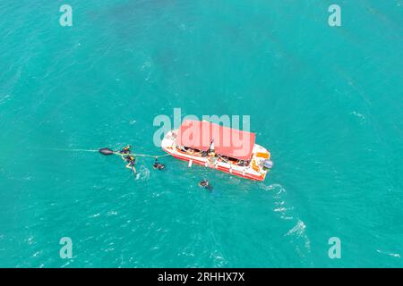 Boot mit Taucheranzug und Flossen im Meer kam in der Lagune an, um nach unten zu tauchen, von oben aus Stockfoto