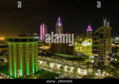 Bei Nacht hat man einen Blick auf die beleuchtete Skyline der Innenstadt von Mobile, Alabama am Wasser Stockfoto