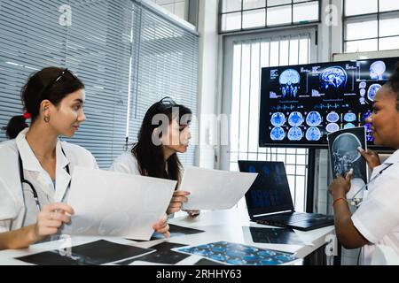 Das Ärzteteam überprüft die Ergebnisse des Scans und schaut sich Monitore im Labor an, teilt medizinisches Wissen und Erfahrungen, von denen ihre Mitarbeiter profitieren Stockfoto