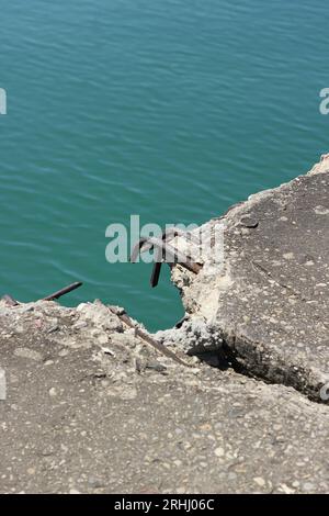 Freiliegende Bewehrungsstäbe, die aus einer gebrochenen Betonplatte ragen. Stockfoto