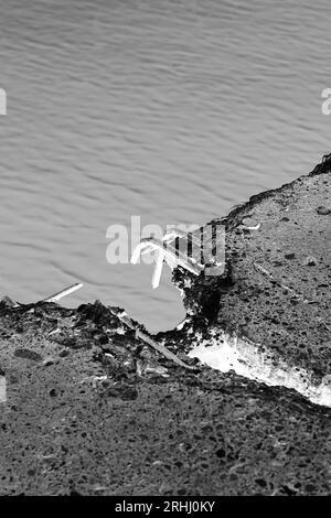 Freiliegende Bewehrungsstäbe, die aus einer gebrochenen Betonplatte in einem schwarz-weißen Monochrom-Filmnegativ ragen. Stockfoto