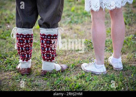 Beine von zwei Personen, eine in traditioneller seto-Volkstracht, die andere in modernen Turnschuhen, Grafschaft Seto, Estland Stockfoto