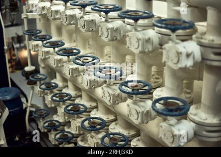 Drosselklappenverteiler im Maschinenraum für Süßwasserfracht mit blauen Ventilgriffen. Stockfoto