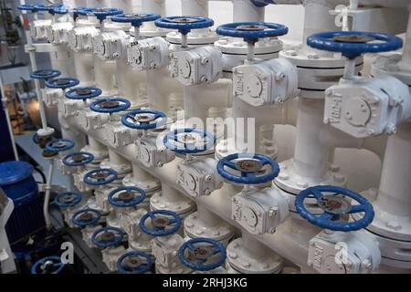 Drosselklappenverteiler im Pumpenraum mit blauen Ventilgriffen. Stockfoto