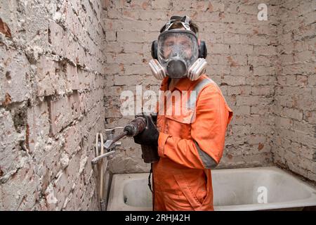 Männlicher Arbeiter, der Vollgesichts-Atemschutzmaske und Gehörschutz trägt, für Arbeiten in staubiger und lauter Umgebung. Stockfoto