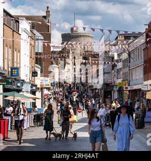 Der runde Turm von Windsor Castle ragt über der Haupteinkaufsstraße der Stadt, der Peascod Street. Windsor, Berkshire, Großbritannien. Stockfoto